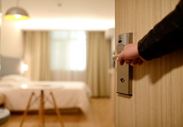 Detail ruky držící kliku pootevřených dveří do pokoje.jpg