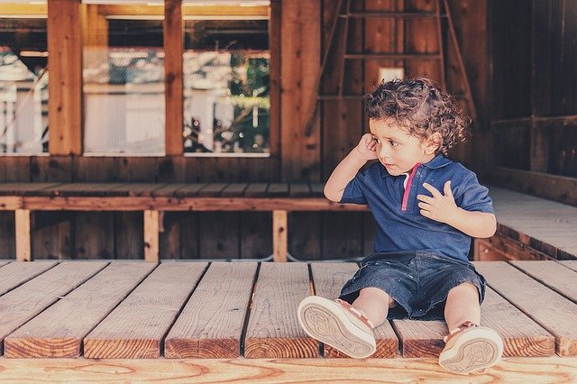 malý chlapec sedící na zemi ve stodole